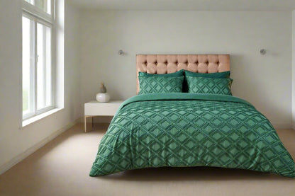 Green patterned bedding set on a bed in a bedroom with a lamp and plant.